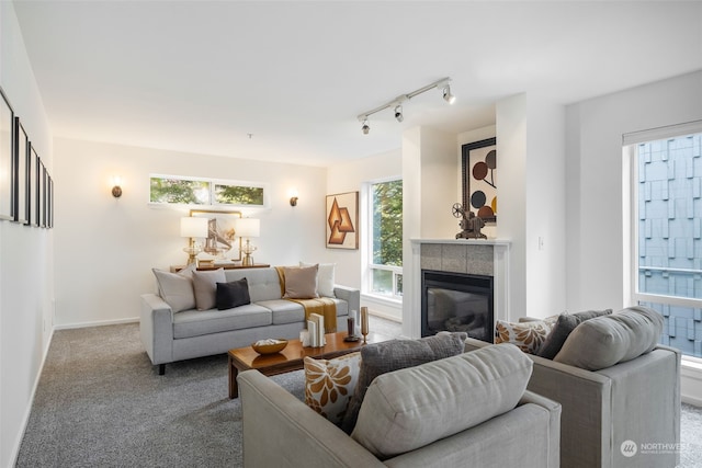 living room with a tiled fireplace, carpet flooring, and track lighting