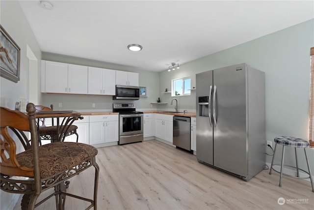 kitchen featuring white cabinetry, appliances with stainless steel finishes, sink, and light wood-type flooring