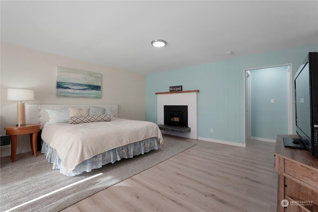 bedroom featuring hardwood / wood-style floors and a brick fireplace