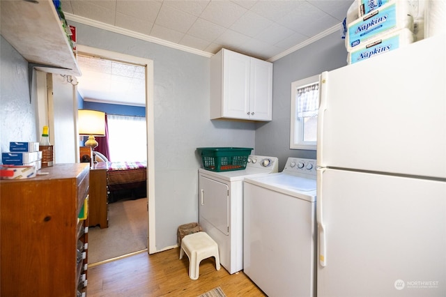 clothes washing area with cabinets, washing machine and clothes dryer, ornamental molding, and a wealth of natural light