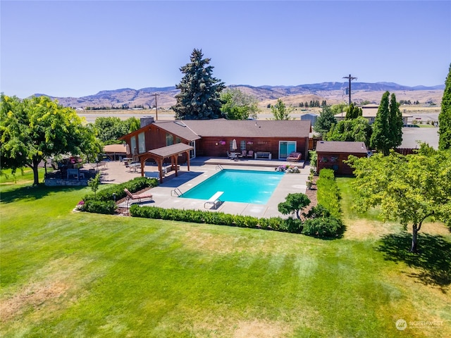 view of pool with a patio, a mountain view, a lawn, and a diving board