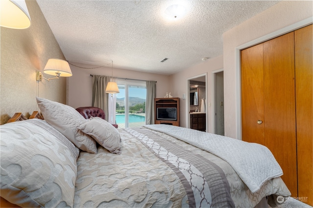 bedroom featuring access to outside, a textured ceiling, a closet, and connected bathroom