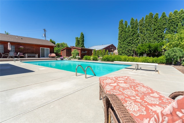 view of pool with a diving board and a patio area