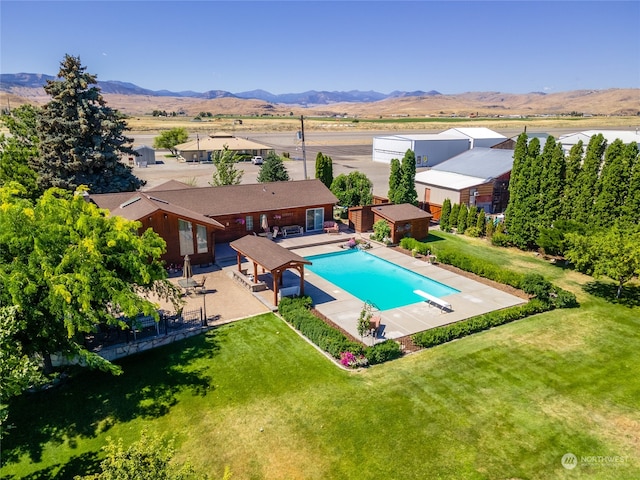 view of pool with a mountain view, a patio area, a yard, and a diving board