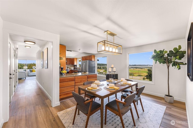 dining space with light wood-type flooring and baseboards