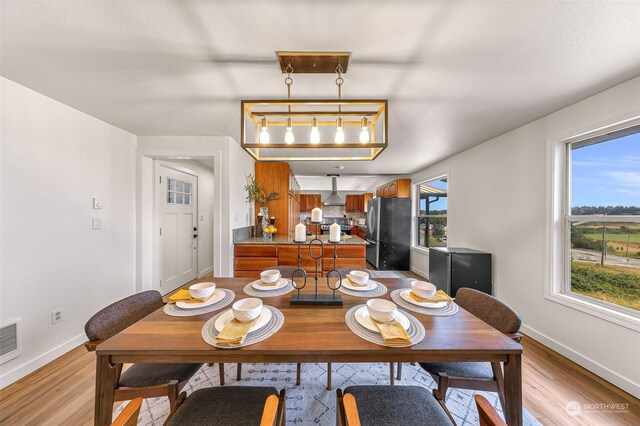 dining space with light wood-type flooring and baseboards