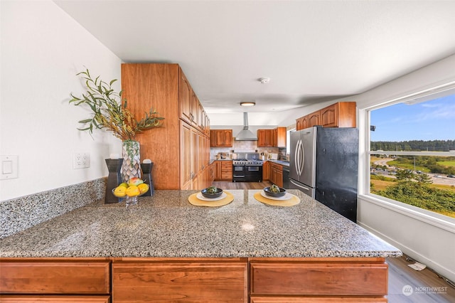 kitchen featuring wall chimney exhaust hood, tasteful backsplash, wood-type flooring, double oven range, and stainless steel fridge