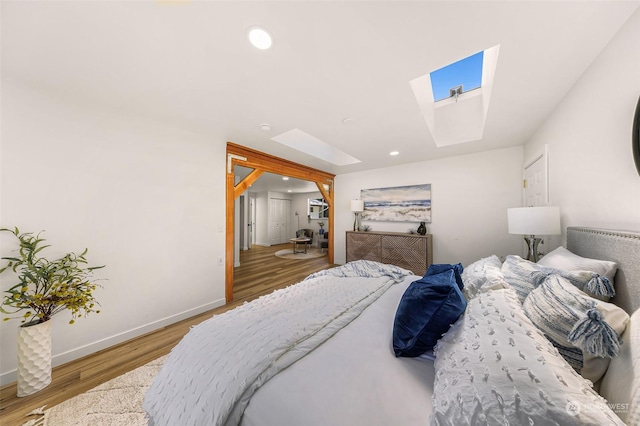 bedroom featuring a skylight, baseboards, wood finished floors, and recessed lighting