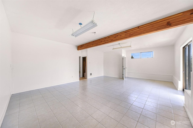 empty room featuring light tile patterned floors, beam ceiling, and baseboards