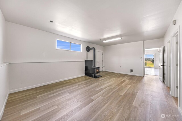 interior space with a wealth of natural light, light hardwood / wood-style floors, and a wood stove