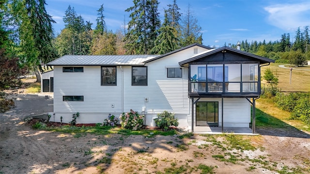 rear view of property featuring a sunroom, metal roof, and a standing seam roof