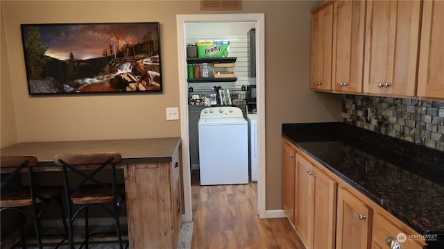 interior space with separate washer and dryer, tasteful backsplash, light wood-type flooring, and dark stone counters