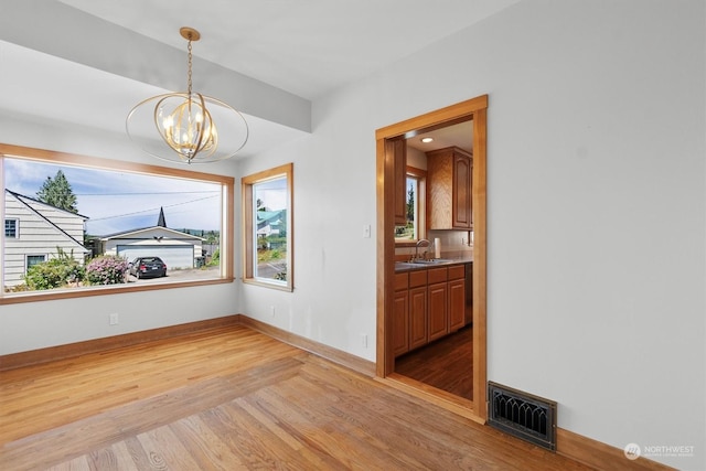 interior space with an inviting chandelier, sink, and light wood-type flooring