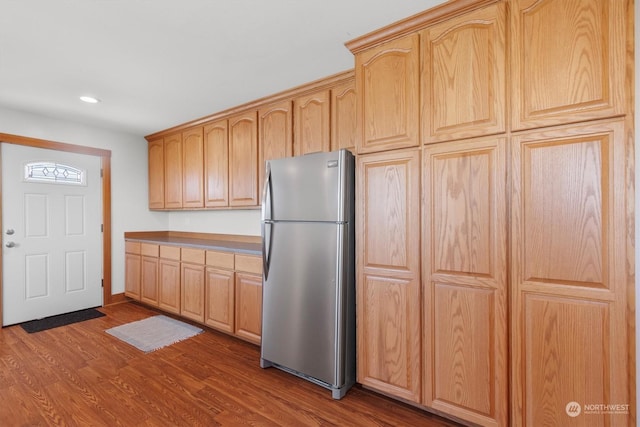 kitchen with dark hardwood / wood-style flooring, stainless steel refrigerator, and light brown cabinets