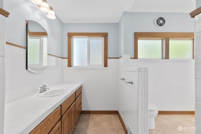 bathroom with tile patterned flooring, vanity, a wealth of natural light, and toilet