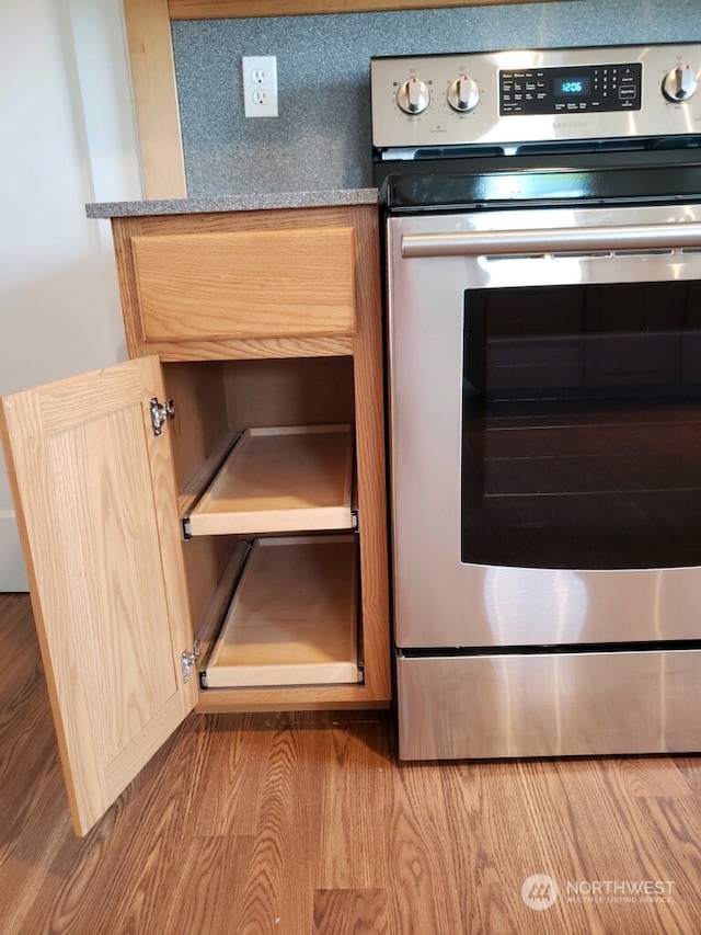 details featuring stainless steel electric range oven, light hardwood / wood-style floors, and light brown cabinets