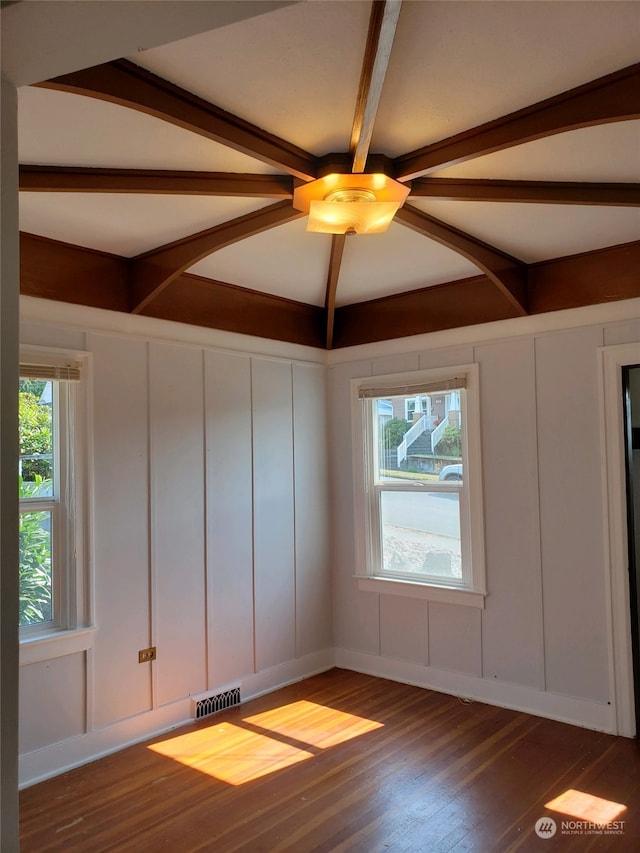 unfurnished room with dark hardwood / wood-style floors, plenty of natural light, and beam ceiling