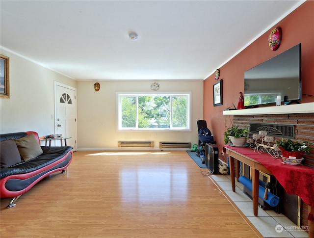 living room featuring a fireplace, a baseboard heating unit, and light wood-type flooring