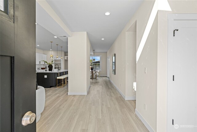 hallway with light hardwood / wood-style flooring and sink