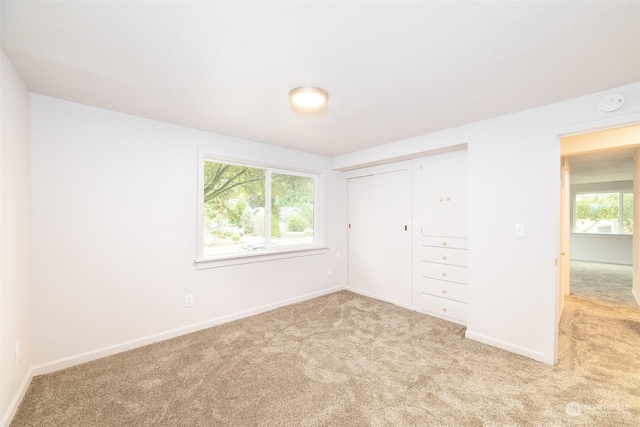 unfurnished bedroom with light colored carpet and a closet