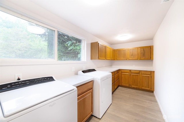 laundry room featuring cabinets, washer and clothes dryer, and light wood-type flooring