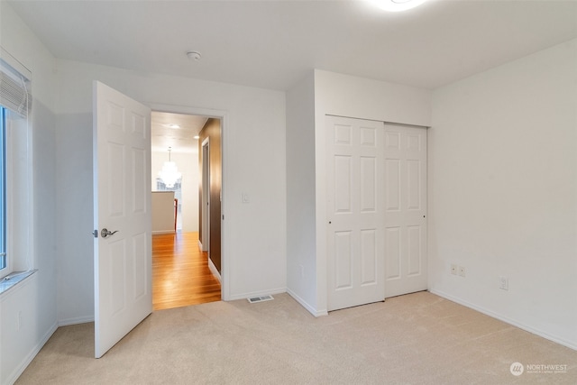 unfurnished bedroom with light colored carpet and a closet