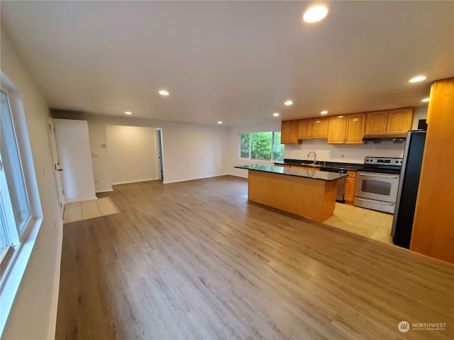 kitchen featuring appliances with stainless steel finishes, sink, a kitchen island, and light hardwood / wood-style flooring