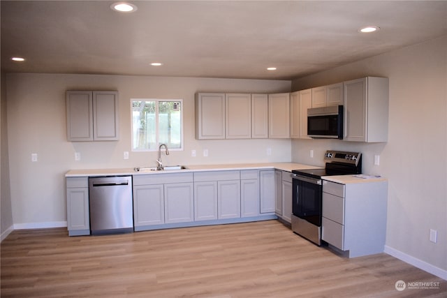 kitchen featuring sink, light wood-type flooring, stainless steel appliances, and gray cabinetry