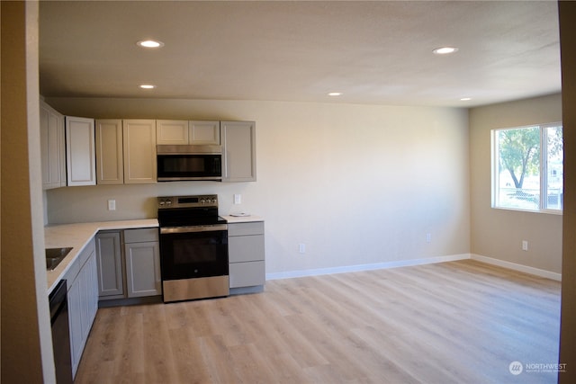 kitchen featuring stainless steel appliances, light wood-type flooring, and gray cabinetry