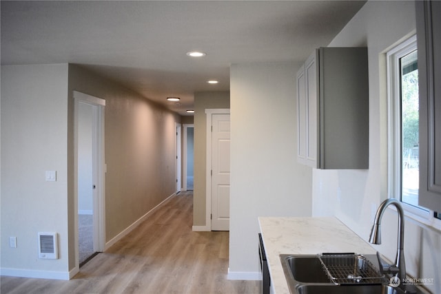 kitchen featuring sink, dishwasher, light hardwood / wood-style floors, and light stone counters