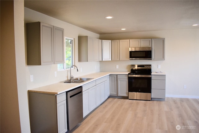 kitchen with light hardwood / wood-style floors, sink, gray cabinetry, and stainless steel appliances