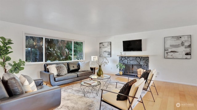 living room with light hardwood / wood-style floors and a stone fireplace