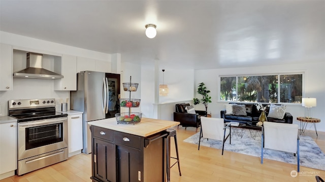 kitchen featuring dark brown cabinetry, light hardwood / wood-style flooring, stainless steel appliances, and wall chimney exhaust hood