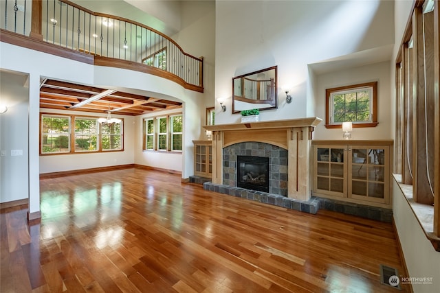 unfurnished living room featuring hardwood / wood-style floors, a tile fireplace, and a healthy amount of sunlight