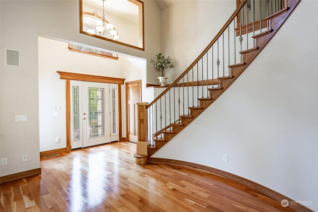 foyer entrance featuring an inviting chandelier, light hardwood / wood-style floors, and a towering ceiling