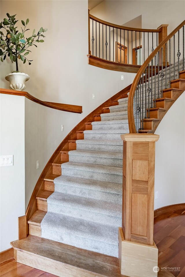 stairs with hardwood / wood-style floors and a high ceiling