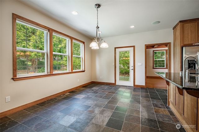 unfurnished dining area with sink, dark tile patterned floors, and a chandelier