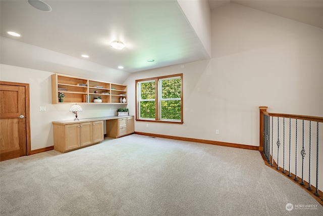 kitchen featuring vaulted ceiling, light colored carpet, and light brown cabinetry