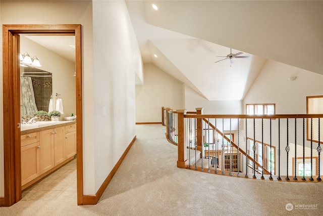 corridor with sink, light carpet, and vaulted ceiling