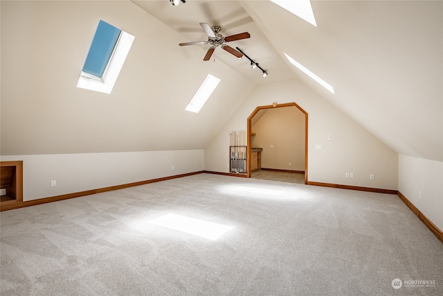 additional living space featuring ceiling fan, vaulted ceiling with skylight, and carpet