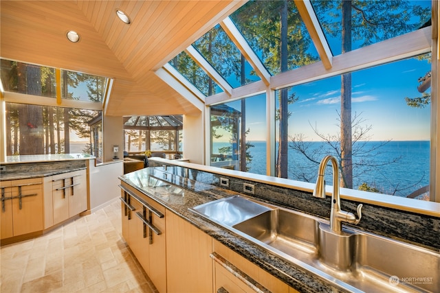 kitchen featuring a skylight, a water view, wood ceiling, and sink