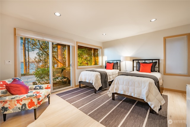 bedroom with access to exterior, multiple windows, and hardwood / wood-style flooring