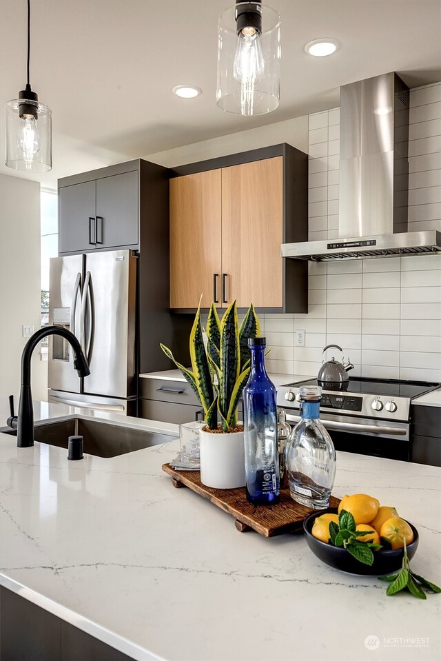 kitchen with decorative light fixtures, tasteful backsplash, wall chimney range hood, stainless steel appliances, and sink