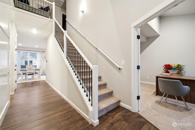 stairway featuring recessed lighting, a high ceiling, baseboards, and wood finished floors