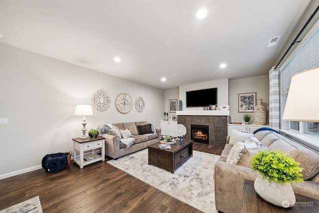 living area featuring visible vents, a tiled fireplace, wood finished floors, recessed lighting, and baseboards