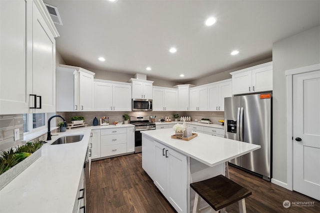 kitchen featuring appliances with stainless steel finishes, dark hardwood / wood-style floors, sink, white cabinets, and a center island