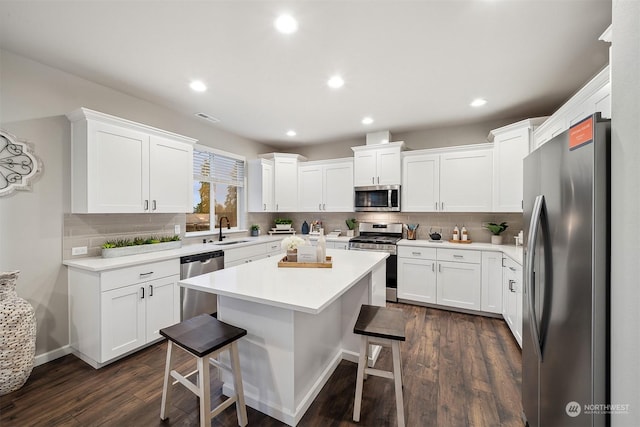 kitchen featuring a kitchen bar, visible vents, a sink, white cabinetry, and appliances with stainless steel finishes