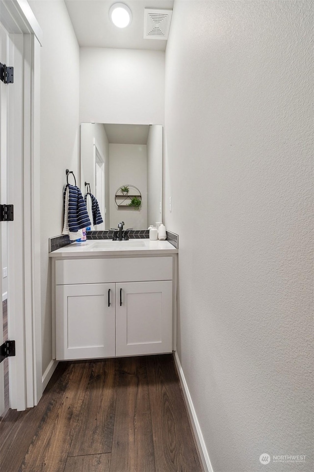 bathroom featuring visible vents, baseboards, wood finished floors, and vanity