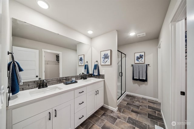 bathroom with vanity, decorative backsplash, and a shower with shower door