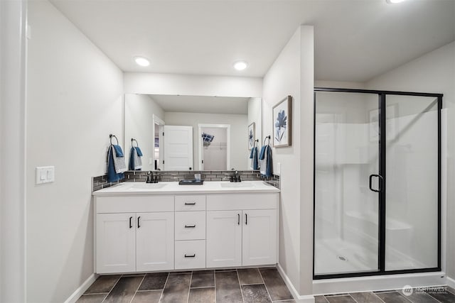 full bath featuring double vanity, a shower stall, a spacious closet, and a sink